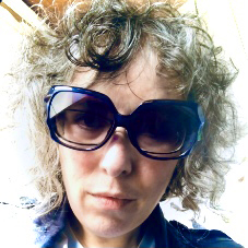 A white woman with grey curly hair and shades